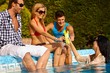 Young friends by swimming pool smiling