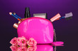 Make up bag with cosmetics and brushes on violet background