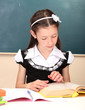 little schoolchild in classroom write in notebook