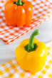Gelbe und orange Paprika auf karierten Servietten.