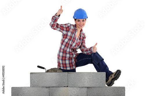 Photo: female mason sitting on a wall making thumbs up sign female mason sitting on a wall making thumbs up sign