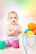 Smiling baby plays with  yarn, on a colored background