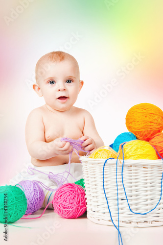 Photo: Smiling baby plays with yarn, on a colored background Smiling baby plays with yarn, on a colored background