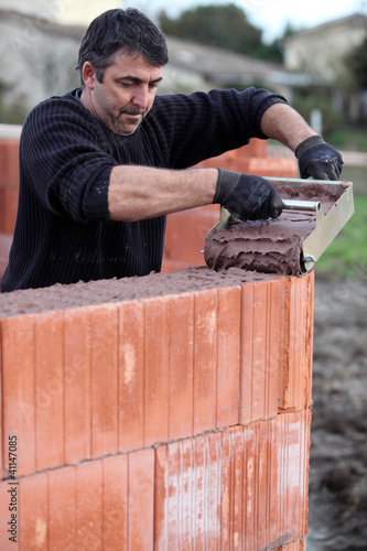 Photo: Mason carefully pouring cement Mason carefully pouring cement