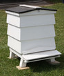 A Traditional White Wooden Beehive on a Grass Lawn.