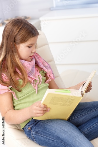 Photo: Little girls reading a book at home Little girls reading a book at home