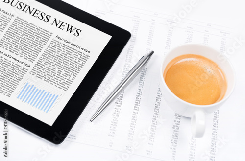 Photo: Modern working place with business news on digital tablet Modern working place with business news on digital tablet