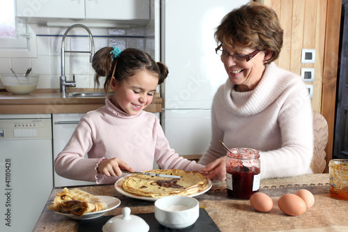 Photo: Young girl preparing crepes with her grandmother Young girl preparing crepes with her grandmother