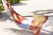 Woman relaxing in the hammock between palm trees