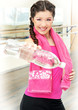 Smiling young woman with bottle of water in gym Smiling young woman with bottle of water in gym