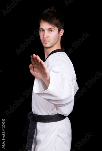 Photo: Young man in kimono make martial arts exercise on black Young man in kimono make martial arts exercise on black