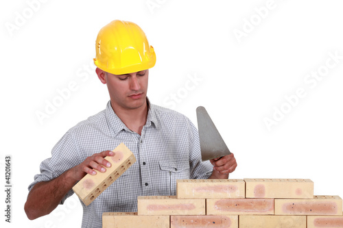 Photo: Mason making brick wall, studio shot Mason making brick wall, studio shot
