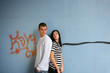 Young couple stood by graffiti covered wall