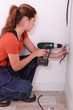 a female electrician working on an electrical outlet