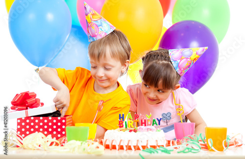 Foto: adorable children celebrating birthday party and opening gift bo adorable children celebrating birthday party and opening gift bo