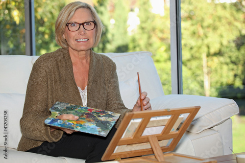 Photo: Woman painting in her home Woman painting in her home