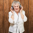 portrait of senior woman listening to music against a wooden wal portrait of senior woman listening to music against a wooden wal