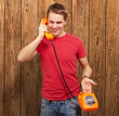 portrait of young man talking on vintage telephone against a woo