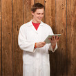 portrait of young academic holding a digital tablet against a wo