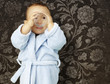portrait of adorable infant with blue bathrobe drinking water ag