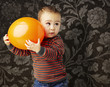 portrait of funny kid holding a big orange balloon against a vin portrait of funny kid holding a big orange balloon against a vin
