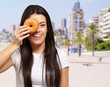 portrait of young woman holding donut in front of her eye agains portrait of young woman holding donut in front of her eye agains