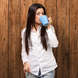 portrait of young woman drinking against a wooden wall