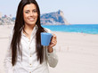 young girl holding cup against a beach