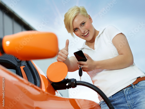 Photo: Woman with cellphone loading electrically powered car Woman with cellphone loading electrically powered car