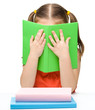 Cute little girl is hiding behind a book
