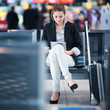 Young female passenger at the airport, using her tablet computer
