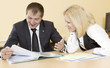 The man and the woman sit at a table and documents look