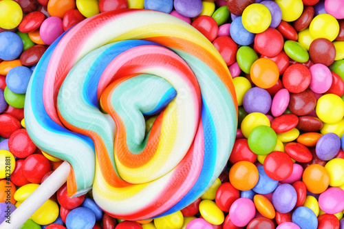 Foto: Striped lollipop and multicolored smarties Striped lollipop and multicolored smarties