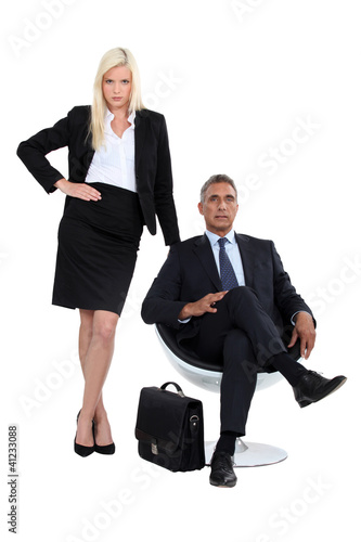Photo: Businessman sitting in a chair next to his glamourous assistant Businessman sitting in a chair next to his glamourous assistant