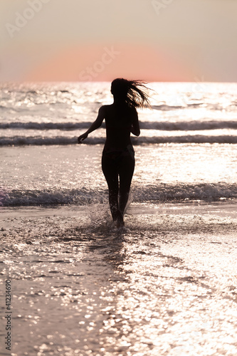 Photo: Silhouette of the girl running across the ocean at sunset Silhouette of the girl running across the ocean at sunset