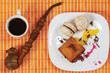 Cup of coffee, tobacco pipe and dessert on a bamboo table cloth