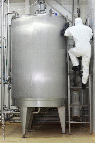 Photo: specialist in uniform climbing a ladder on industrial tank specialist in uniform climbing a ladder on industrial tank