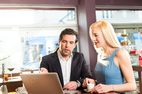 Photo: Working colleagues - a man and a woman - sitting in cafe Working colleagues - a man and a woman - sitting in cafe