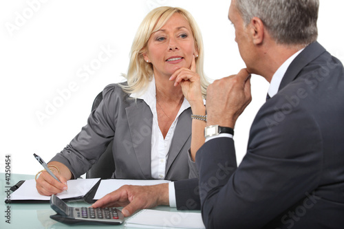 Photo: Mature business couple at a desk with a calculator Mature business couple at a desk with a calculator
