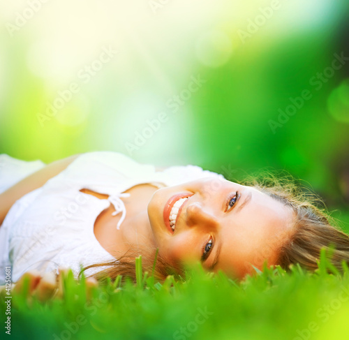 Photo: Spring Girl lying on the Field. Happiness Spring Girl lying on the Field. Happiness
