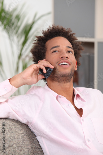 Photo: Man at home talking on the telephone Man at home talking on the telephone