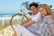 Couple with bikes sitting on the sand dunes