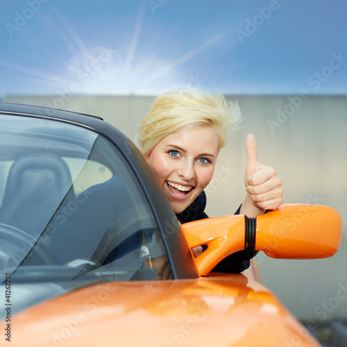 Foto: Beautiful 20s driving a roadster and shows thumb up Beautiful 20s driving a roadster and shows thumb up