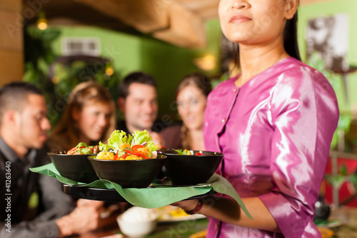 Foto: Junge Leute mit Bedienung essen in einem Thai Restaurant Junge Leute mit Bedienung essen in einem Thai Restaurant