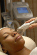 Mujer morena aplicando láser facial en un spa.Tratamiento facial