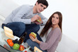 Young couple eating burgers on sofa