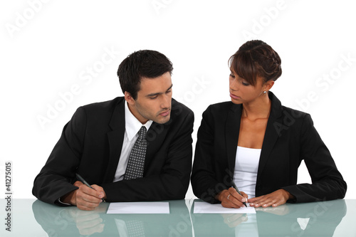 Photo: Two business people comparing notes Two business people comparing notes
