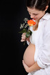 pregnant woman with rose against black background