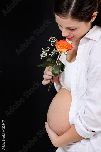 Photo: pregnant woman with rose against black background pregnant woman with rose against black background