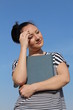 Brunette young woman holding book and thinking, outside